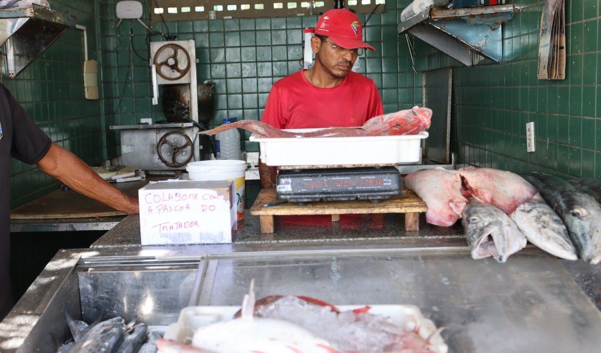 homem pesando um peixe